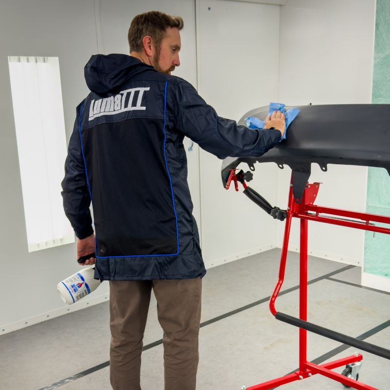 Person cleaning a car roof with a blue towel in a garage setting wearing a Luma III Lab Coat